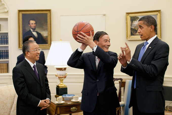Chinese Vice Premier Wang Qishan holds an autographed basketball given to him by President Obama. He and President Obama are talking as Chinese State Councilor Dai Bingguo looks on.