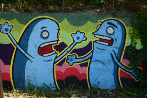 Cartoonish painting on a wall showing two blue characters involved in an argument or disagreement.