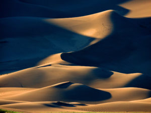 Photo of hiker on dramatic sand dune ridges.