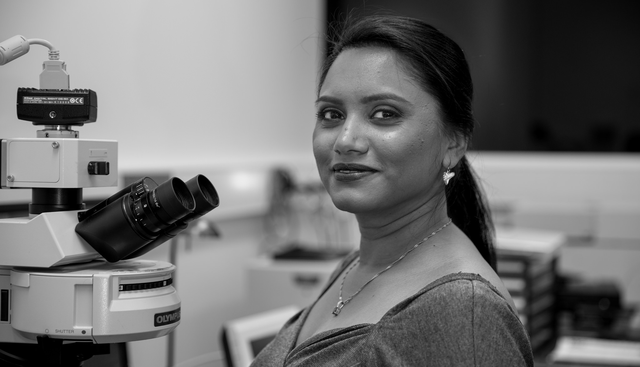 Woman standing in front of a microscope