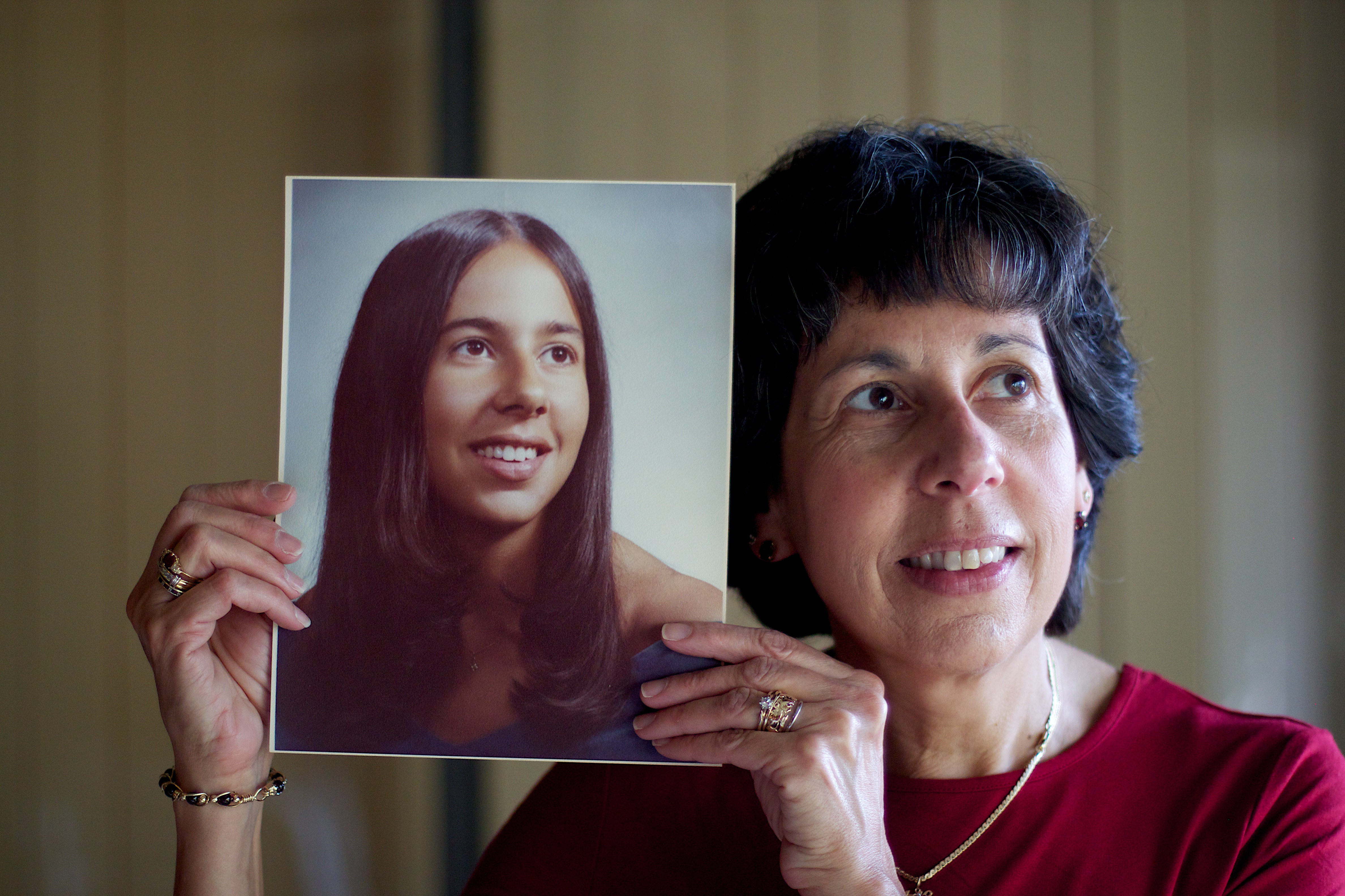 Middle-aged woman holding a picture of her younger self.