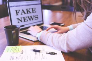 A laptop with the words "fake news" on the screen.