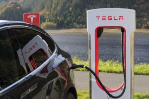 A black Tesla car hooked up to a Tesla charging station.