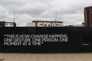 A quote on a the side of the building that reads "This is how change happens. One gesture. One person. One moment at a time." with the name "Libba Bray" written next to it. 