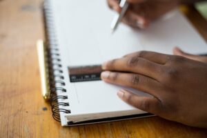 Person writing in notebook making columns with ruler