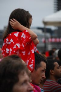 A child sitting on a man's shoulders and covering her hears