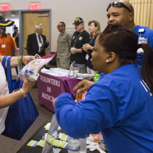 A woman distributing medicine, wearing a volunteer uniform