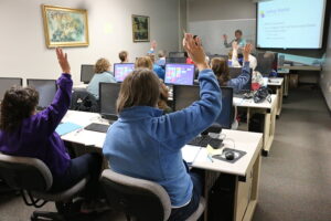 Group of people listening to presentation and raising their hands