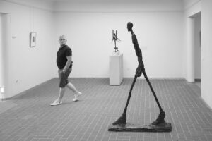 Man striking same pose as a sculpture in an art gallery