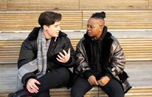 Two transmasculine people sitting together and having a serious conversation.