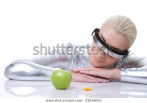 Stock photo with watermark of a woman wearing futuristic glasses and looking at an apple