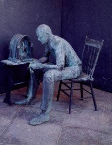 Bronze sculpture of a man sitting in a chair listening intently to the radio 