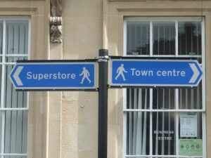 Two roadsigns pointing in opposite directions. One points to Superstore, the other to Town centre