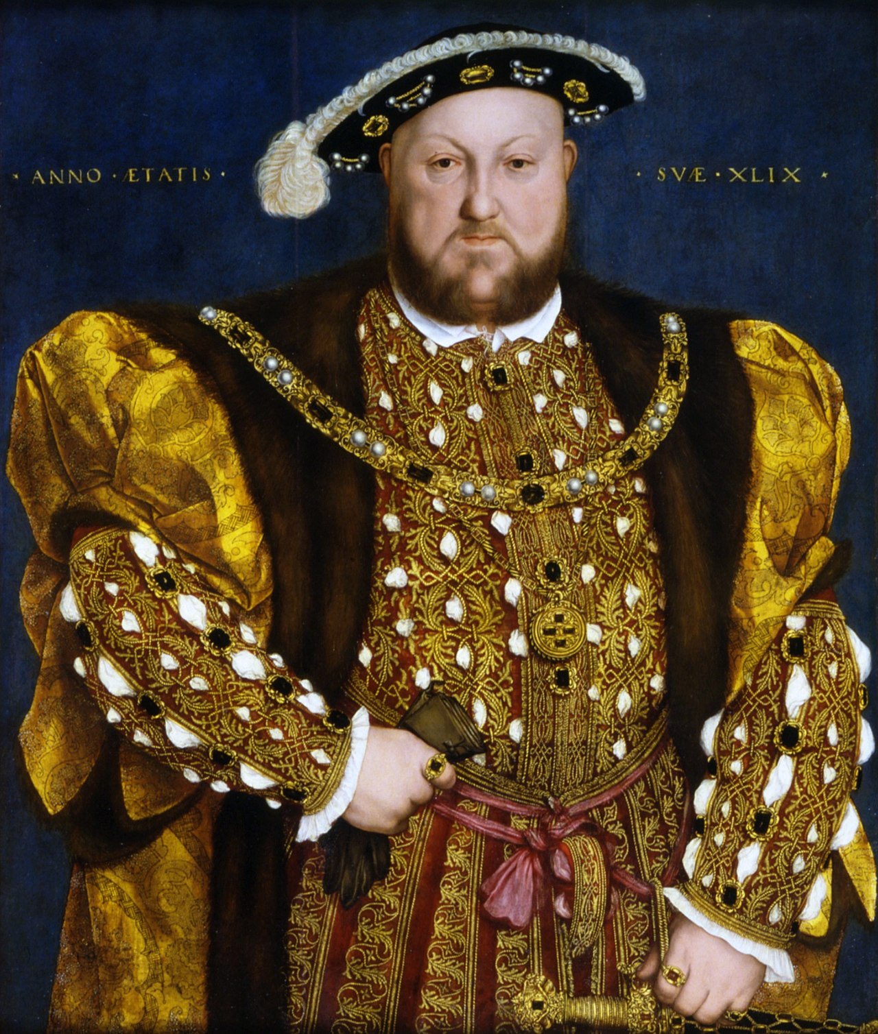 Henry VIII in regal clothing. He is a large, round-faced man with a brown beard, wearing a gold blouse and brown vest, as well as a hat.