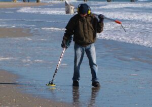 Person using metal detector on the beach.