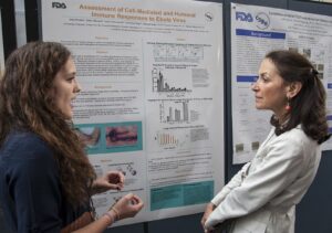 Two women talking in front of a poster about research