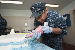 A man in uniform decorating a cake