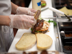 A person putting together a sandwich in a sandwich shop