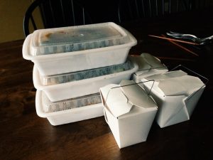 Takeout food in white cardboard and plastic containers