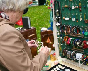 A person at a flea market looking at wooden glasses frames and jewelry