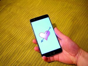 A hand holding a smartphone with a graphic of a heart on it