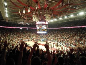 A basketball court seen from the stands through a sea of raised hands