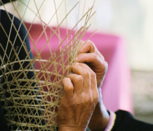 a close-up of a basketweaver weaving a basket