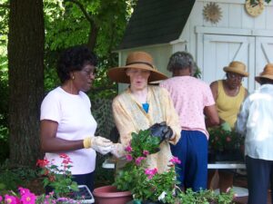 A group of people working with potted flowers