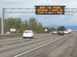 Highway sign that says: Drop the phone because I said so that's why -- Mom