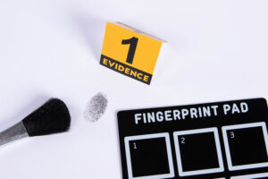 A fingerprint duster, fingerprint pad, and evidence marker with the number 1