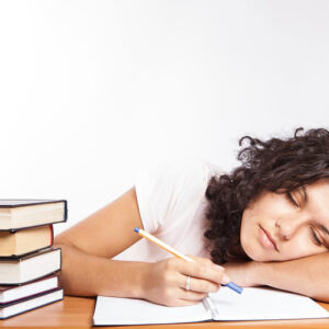 Young woman sleeping on her notebook while studying