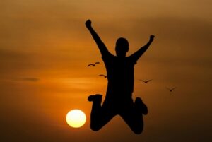 A person jumping for joy in front of a sunset