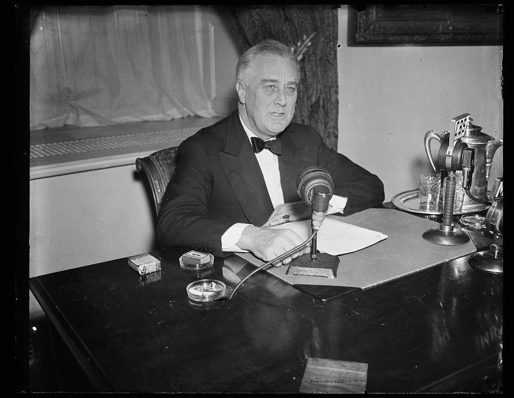 A photograph of Franklin Roosevelt discussing his First New Deal over radio broadcast.