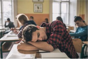 A student napping on a desk in a classroom