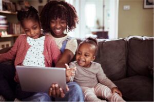 A mom and two children looking at a tablet together and smiling