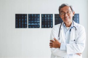 A doctor smiling in front of several MRI scans