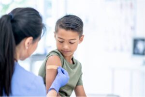 A child getting a bandaid put on his upper arm by a doctor.