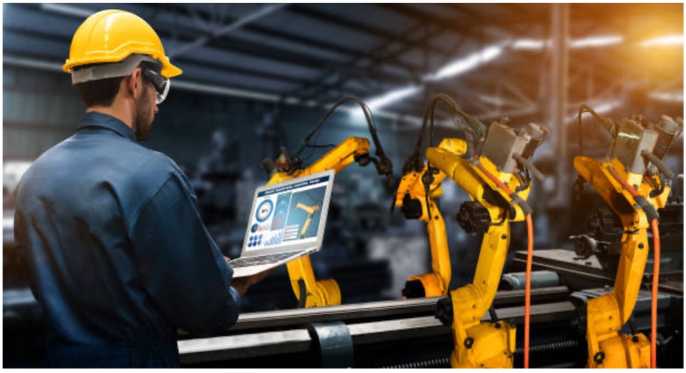 A construction worker looking at a machine in person and on the computer.