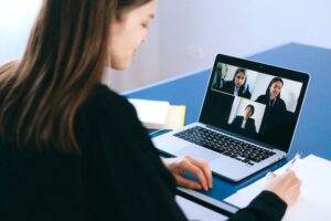 woman sitting at a laptop showing a video conference with 3 other women