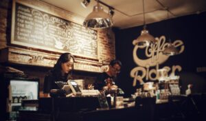 two workers behind the counter at a coffee shop