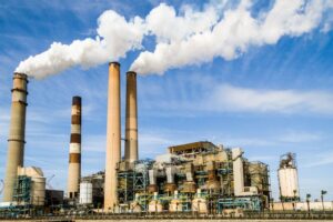 factory with white smoke emitting from smokestacks