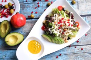 salad composed of vegetables and quinoa with a side of yellow dressing