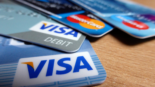 Close up of corners of four credit cards on a table, fanned to show their logos: 2 Visas and 2 Mastercards