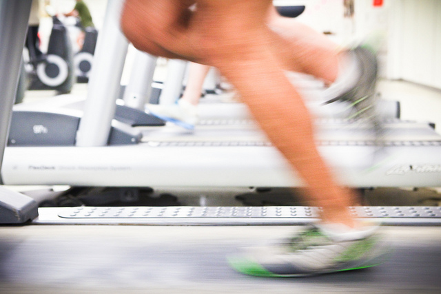 Blurry legs running on a treadmill, with other gym equipment visible in the background