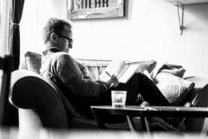 Man writing in a notebook sitting on a couch.