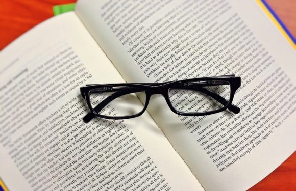 Open book with folded glasses on top