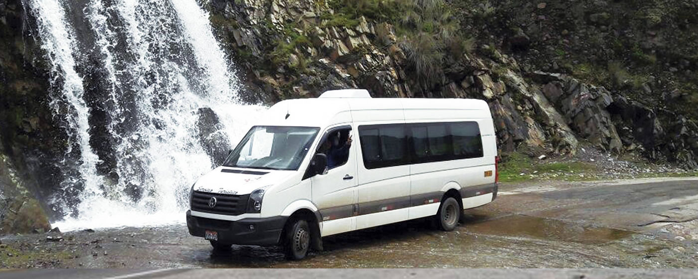 Minivan blanca frente a cascada
