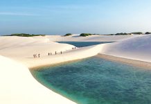 Viajeros caminando por desierto y lagunas color esmeralda en Brasil