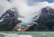 Glaciar entre montañas y frente a lago