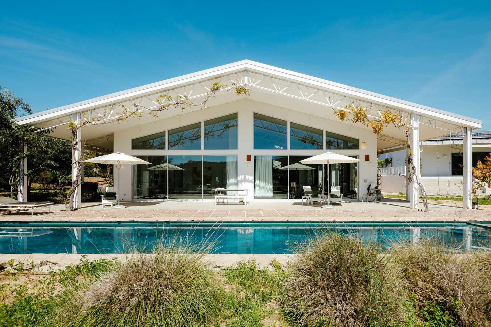 The energy-efficient residence comes with solar panels, thriving gardens, a large pool patio, and a guesthouse.